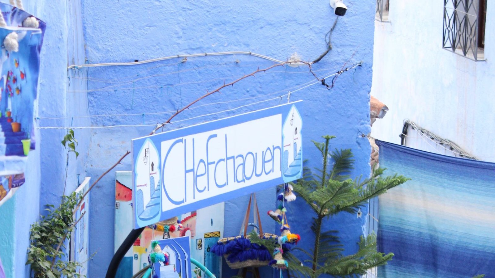 A hand-painted Chefchaouen sign hanging in a blue-washed lane of the medina