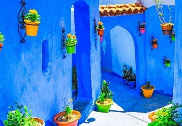 A blue-painted courtyard hung with terracotta pots, Chefchaouen