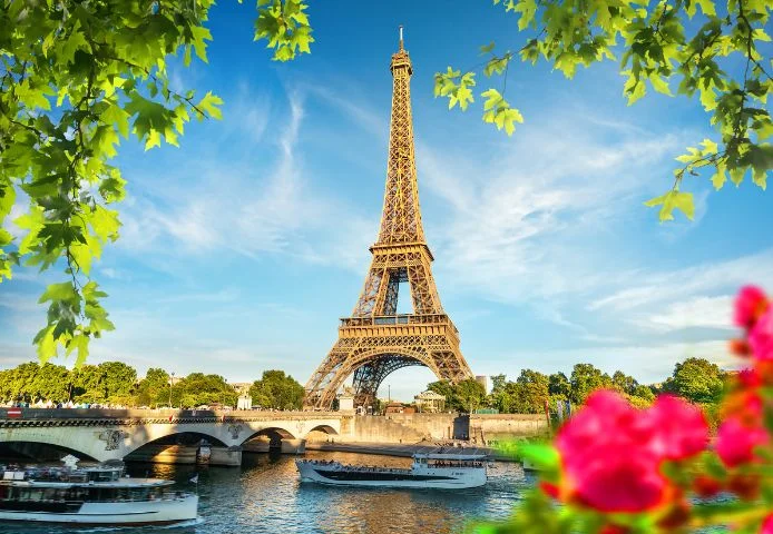 The Eiffel Tower seen across the Seine with a sightseeing boat passing below